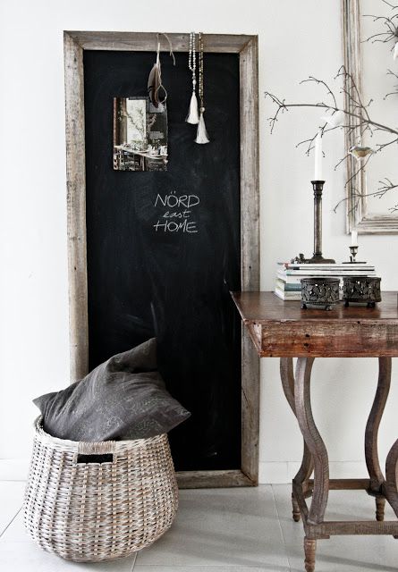 large mirror with chalkboard paint next to antique wooden desk and basket filled with blankets