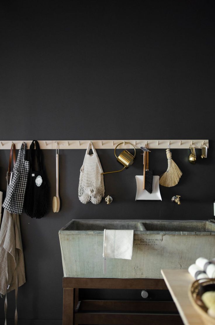 Dark monochrome wall in kitchen with wooden pegs and slate double sinks