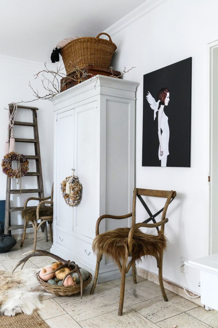 Beautiful Scandinavian room with white armoire, graphic black and white painting and rattan chair with flokati throw