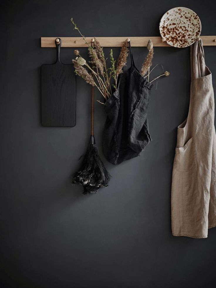 Close up of wooden pegs on a dark monochrome wall with hanging basket of flowers and burlap apron