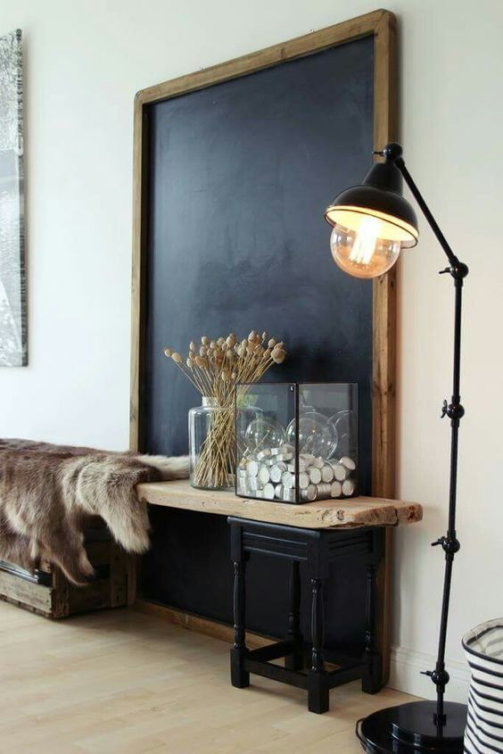 Oversized chalkboard in front of wooden bench draped with fur throw