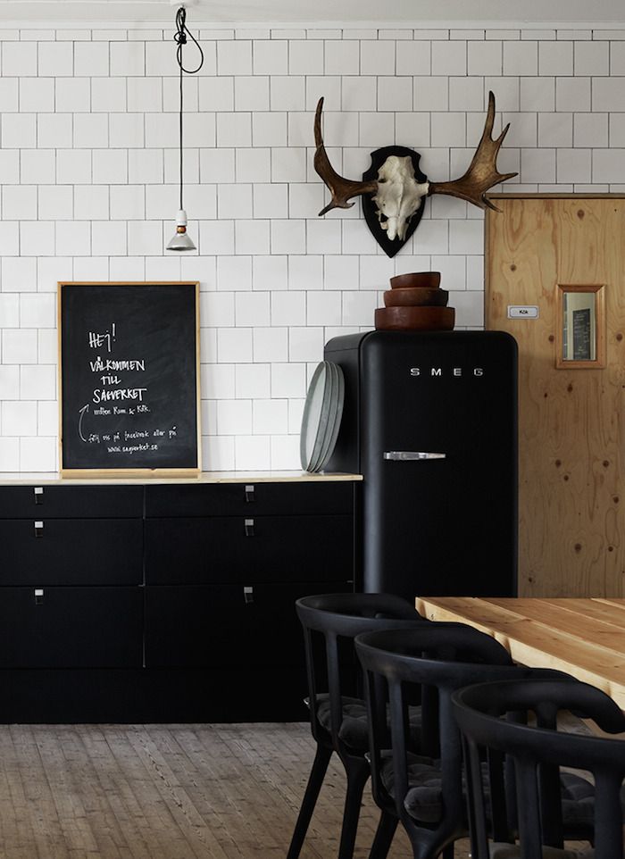 Black Smeg refrigerator with subway tiles and mounted elk antlers