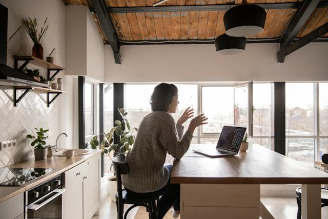 Woman working on her laptop at a kitchen island.
