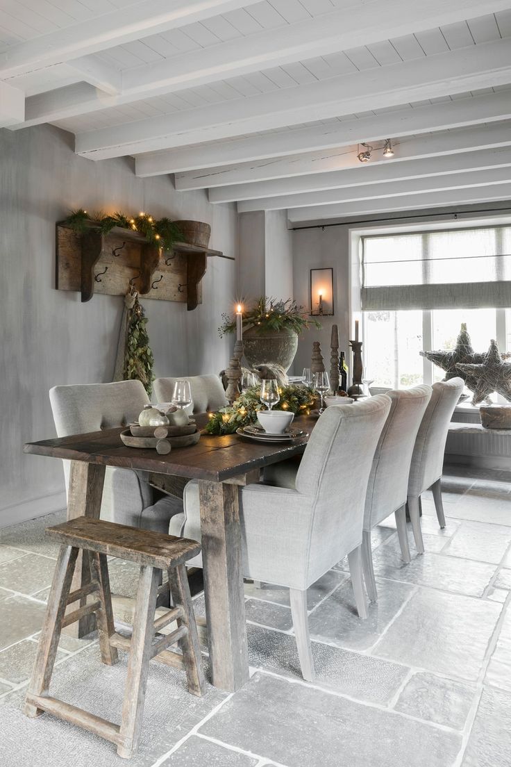 Gorgeous holiday kitchen table with upholstered side arm chairs, gray tiled floors and wooden beams