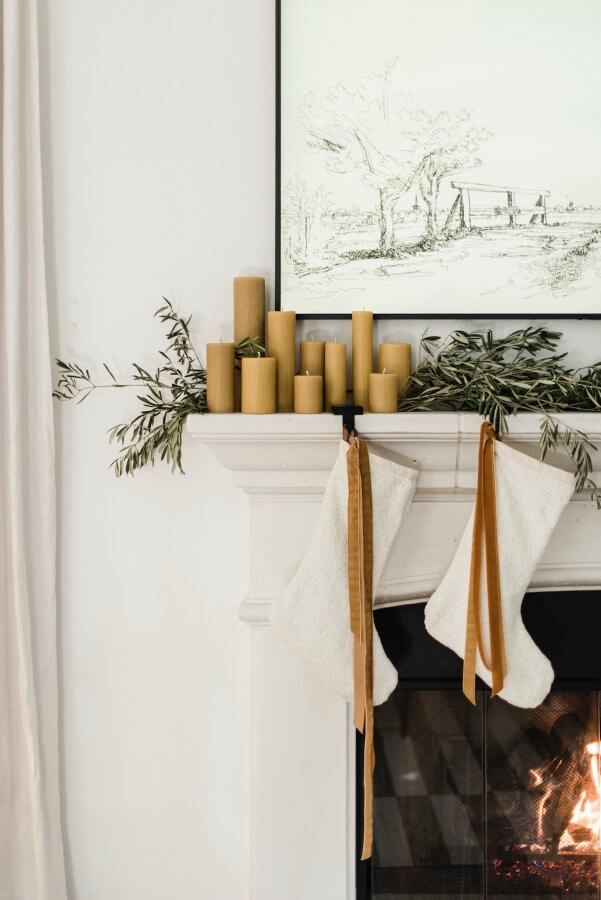 Elegant white mantel with white stockings and gold velvet ribbon with beeswax candles