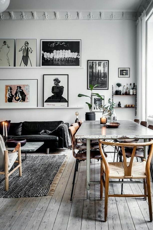 Beautiful Parisian kitchen with white moulding, weathered wooden floors and marble-topped dining table with wooden chairs and dramatic gallery wall