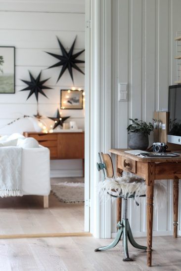 White room with white wood walls, iron starbursts on walls, wooden desk with computer
