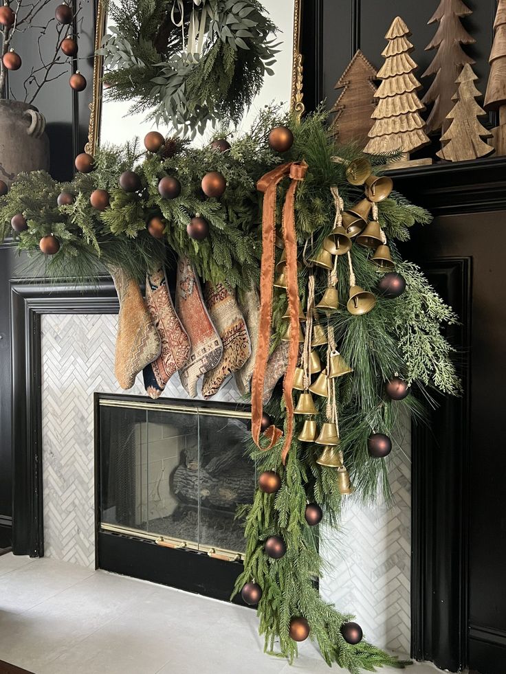 Beautiful Christmas mantel with black walls, natural pine garland, antique bells and vintage stockings