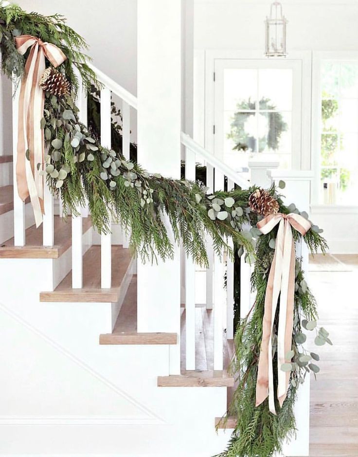 Bright white staircase with festive pine garland laced with eucalpytus and gold bows