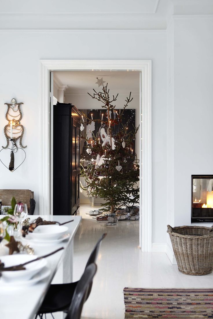Doorway leading to real Christmas tree with lit candles and silver snowflake ornaments