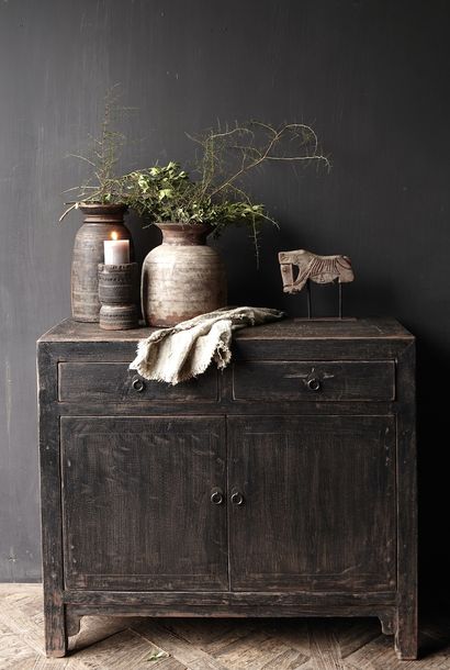 Weathered black 2 door chest with plants and candle in front of chalkboard paint wall
