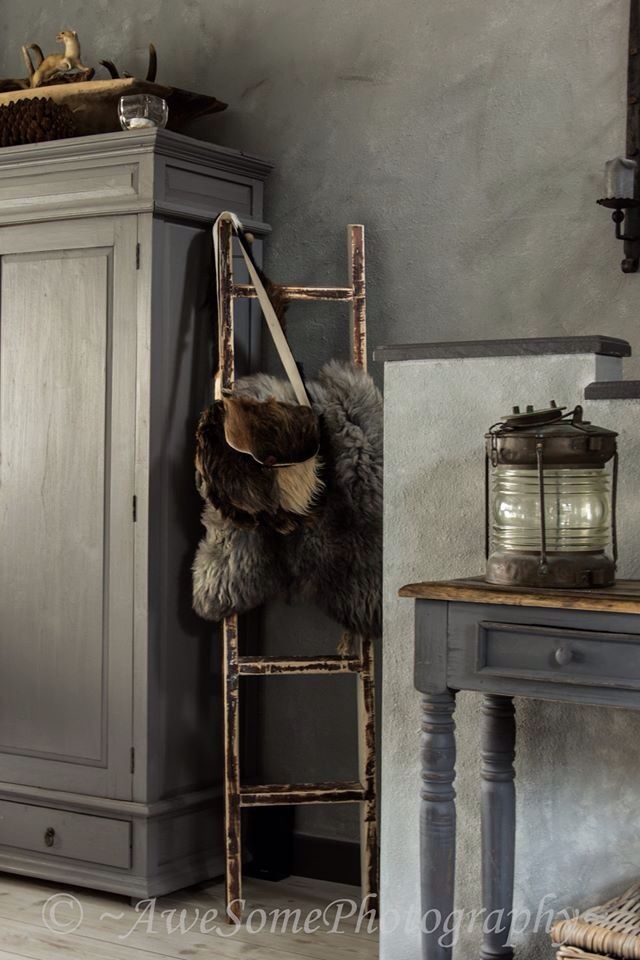 Lime wash wall with vintage ladder in corner with leather bag and furry throw