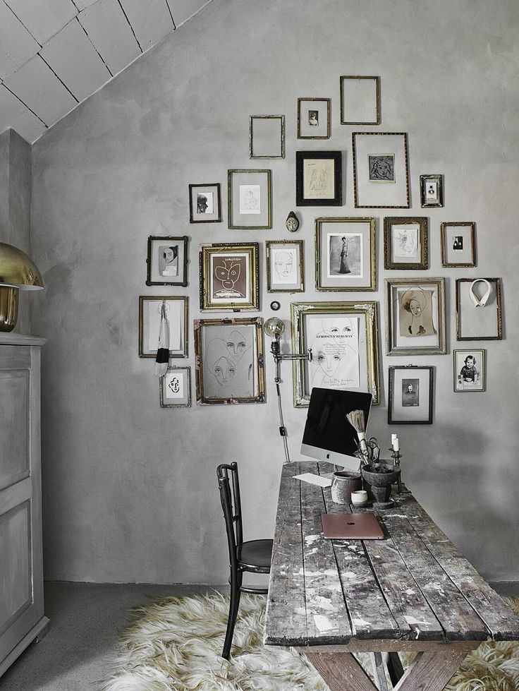 Lime wash wall with vintage wooden picnic table style desk and gallery wall with vintage gold frames