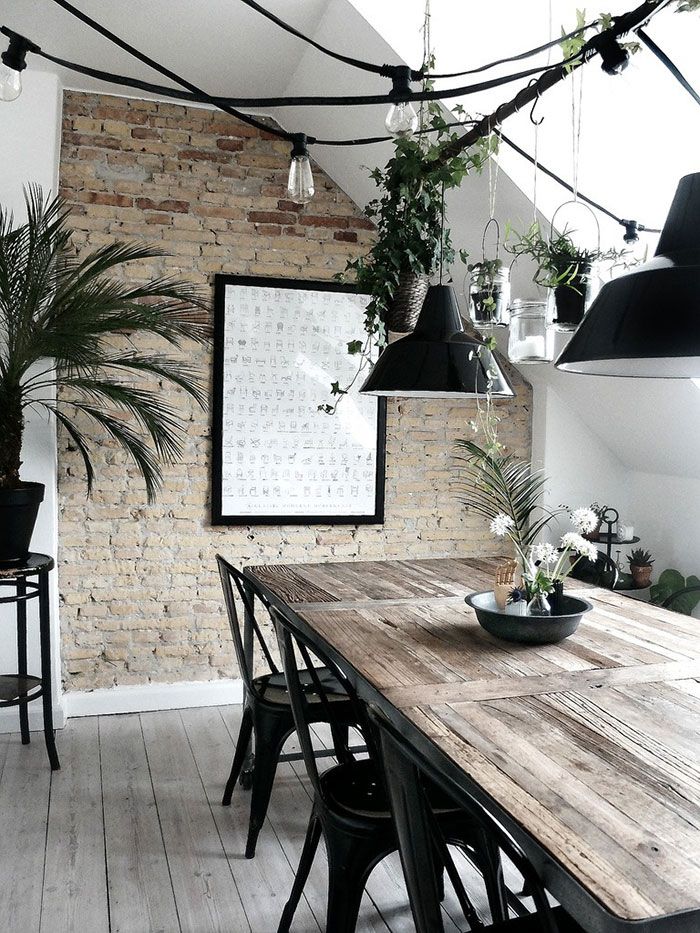 Kitchen alcove with exposed brick wall, wood top table, black metal Tolix chairs and garlands of exposed Edison bulbs