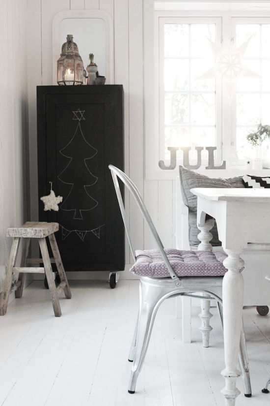 Light bright Scandinavian kitchen with white wooden table and white Tolix chair with lavender cushion