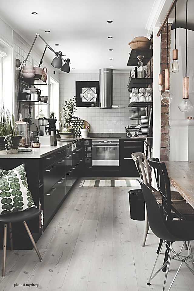 Sleek kitchen with white subway tile, silver appliances, black matte cabinetry and Scandinavian decor touches
