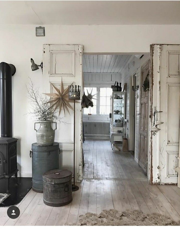 Entryway in cottage with chippy whit wooden doors and wide plank worn hardwood floors