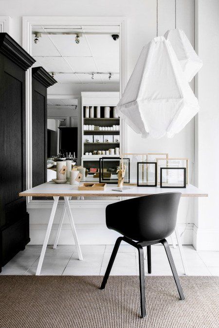 Corner office space with crisp modern white walls, glossy white trestle desk and hanging fabric pendant lamps