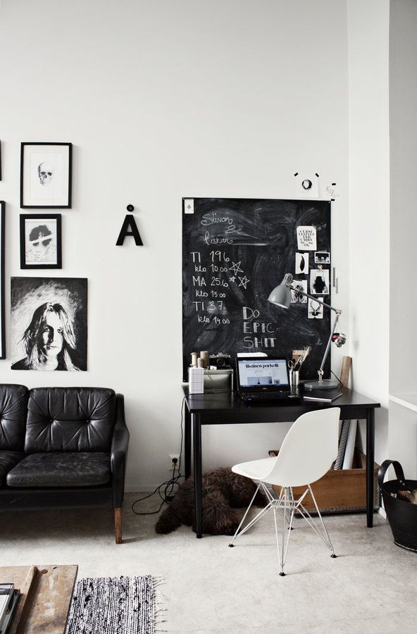 Home office with black and white graphic collage art, chalkboard above desk and white modern chair with silver lamp