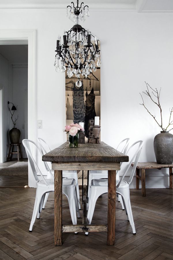 Beautiful white dining room with wooden table and white tolix chairs and crystal chandelier