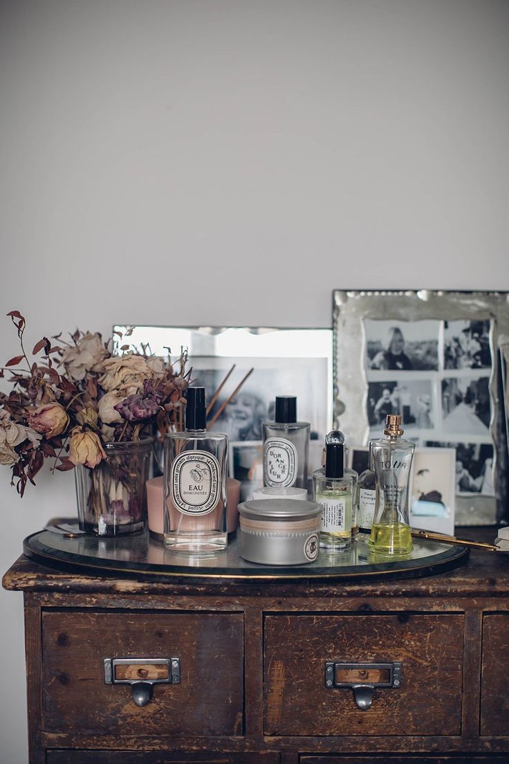Display of Diptyque candles and perfume bottles on a silver tray on a wooden vintage card catalog