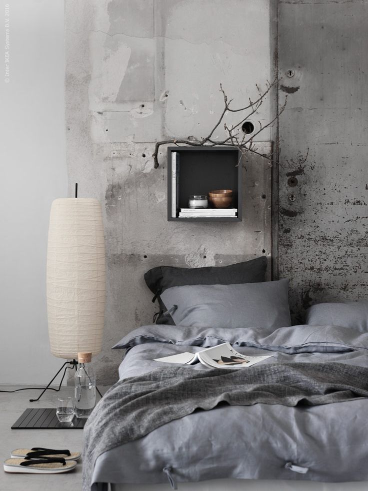 Beautiful light blue bed on floor with concrete wall and branches sitting on a shelf on wall