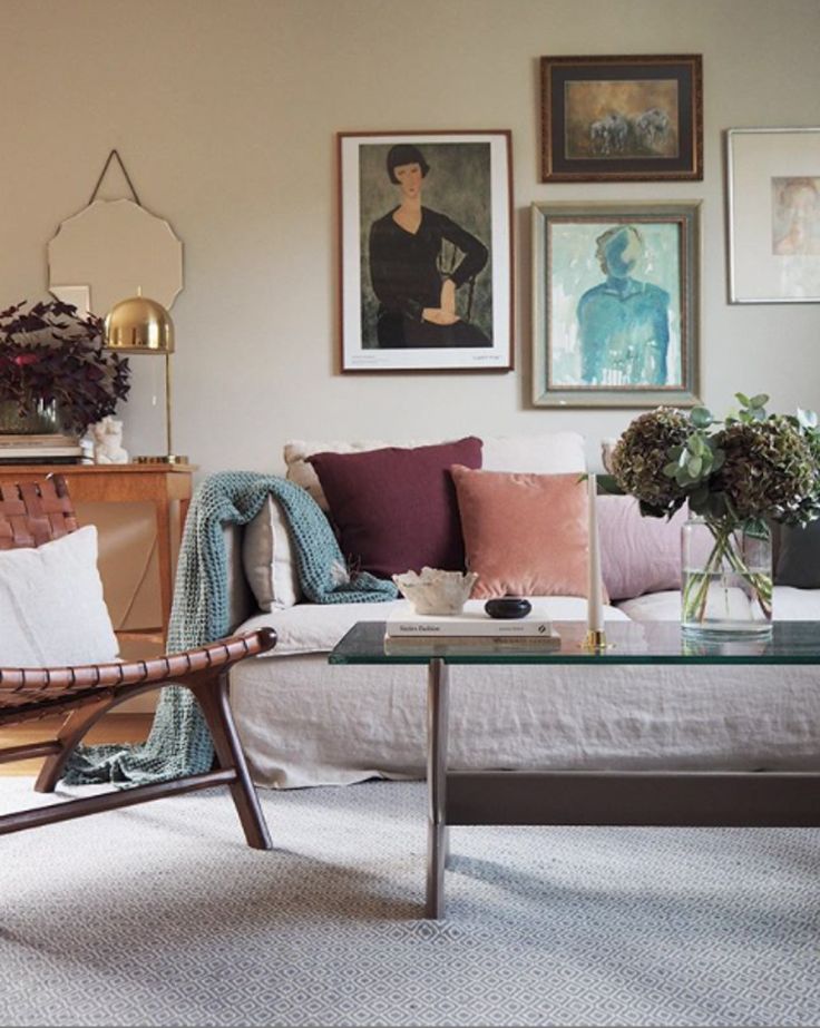 Gallery wall with vintage oil paintings above a slipcovered sofa with velvet pillows