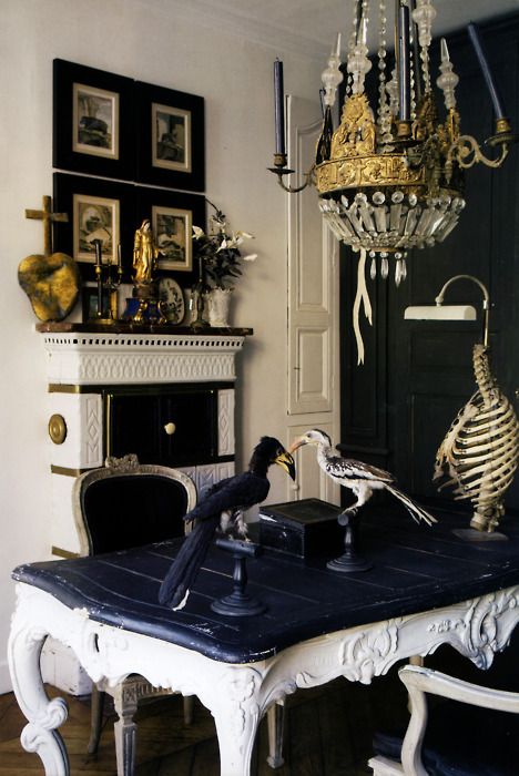 Ornate dining room with crystal chandelier, brass fixtures and taxidermy birds on table