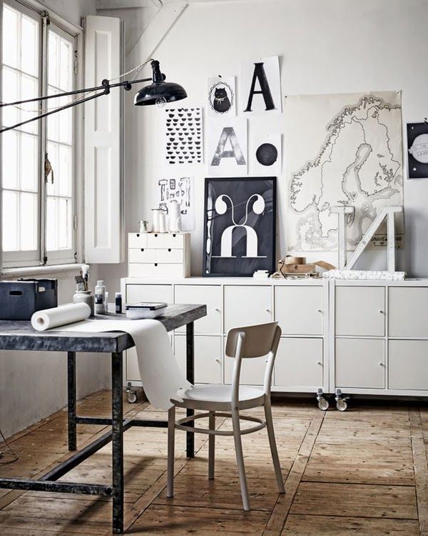 Light filled corner office space with white built-in cabinets, wooden desk and chair and inspiration gallery wall with black and white artwork
