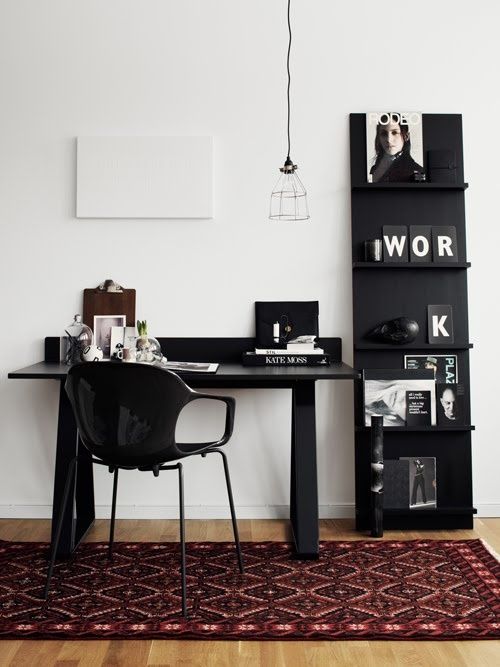 Minimal home office with modern black chair and small black bookshelf with magazines and block letters spelling out WORK