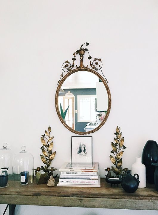 Wooden trestle table with stack of books, framed black and white photo with ornate vintage mirror above