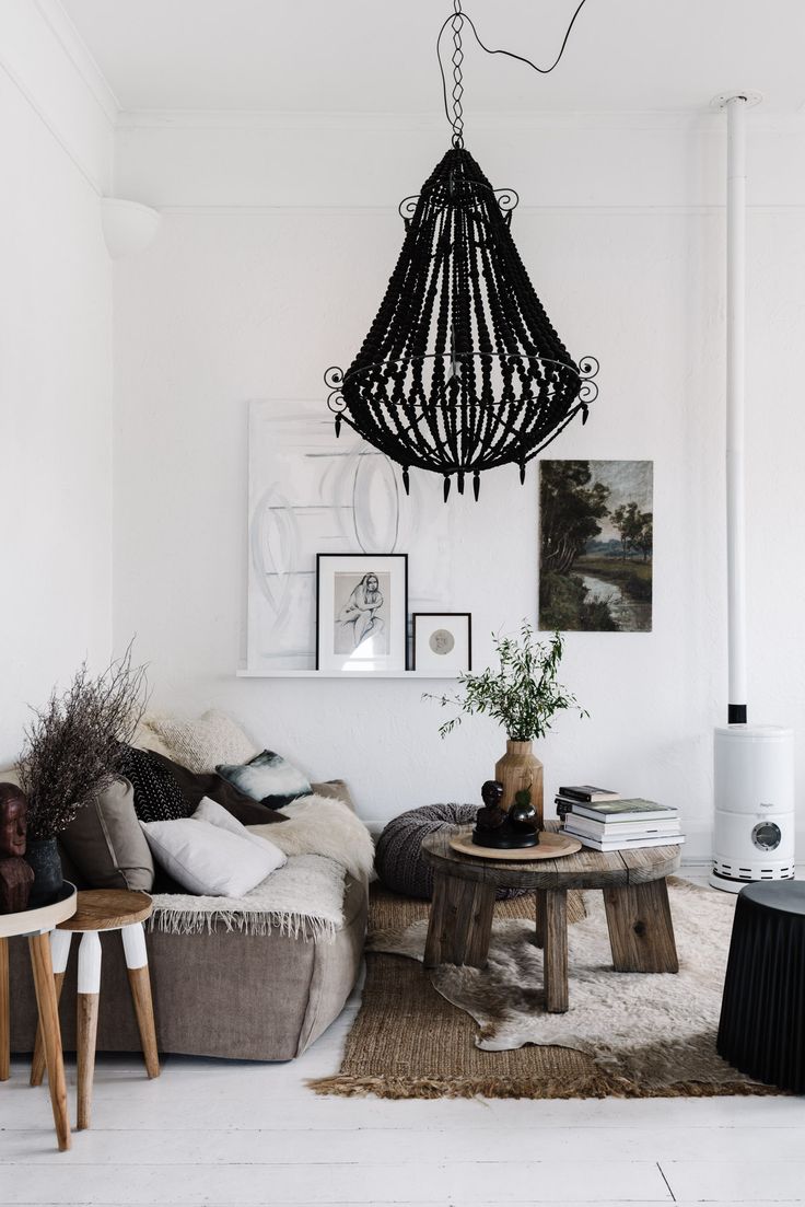 Bold black hanging beaded chandelier in simple sitting room with wooden coffee table and shabby sofa