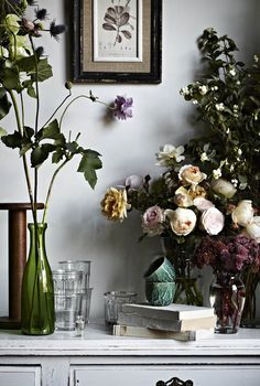 A vintage-themed workspace featuring colorful hydrangea blooms in a glass vase, surrounded by art books and paintings of contemplative figures.