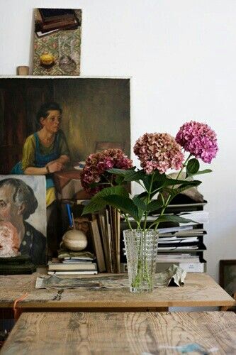 A charming display of framed botanical prints, blush roses in a bottle vase, and eclectic décor on a rustic mantel.