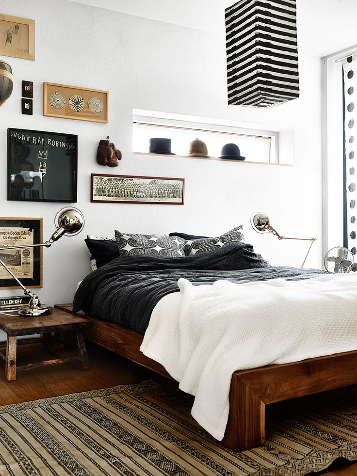 Bedroom featuring a gallery wall above a wooden bed, with a mix of framed artwork, vintage decor, and bold patterns, adding a rustic and eclectic vibe to the room.