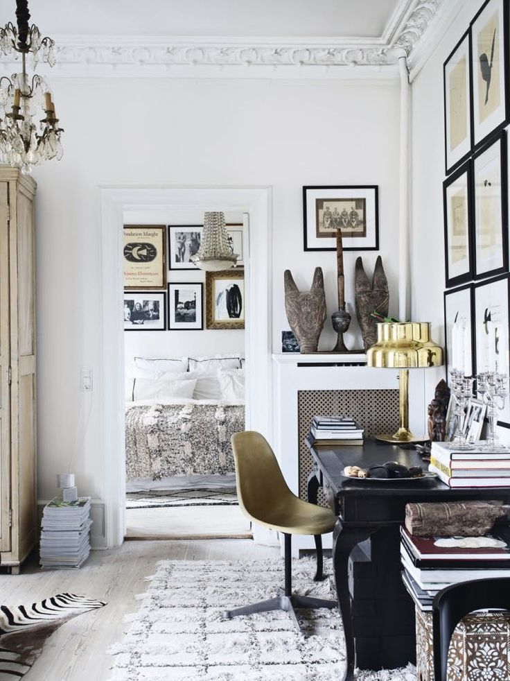 A living room featuring a rustic wooden coffee table, two leather armchairs with throw pillows, and a decorated mantel displaying vintage-style portrait art in various frames