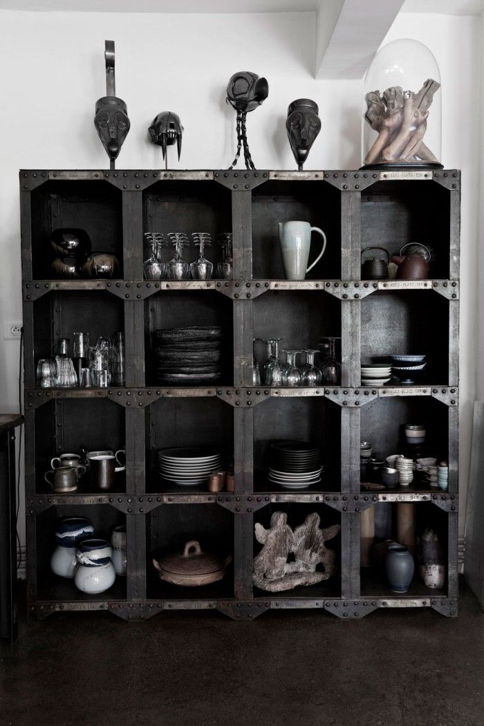 Bold black industrial shelving unit with metal detailing, neatly displaying ceramics, glassware, and eclectic sculptures, adding texture and depth to the space.