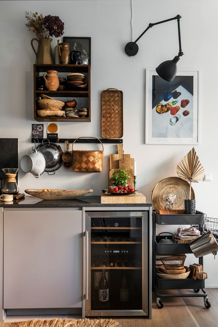 Boho kitchen decorating with a focus on organization, showing a neatly arranged open shelf, wall-mounted tools, a designated coffee station, and a tidy rolling cart next to a wine cooler.