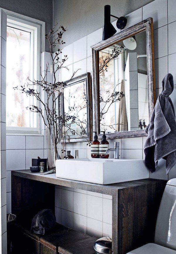 A black and white bathroom with a clawfoot tub. The lower half of the wall is black wainscoting, and the upper half is white. A chair with a towel on it sits next to the tub.