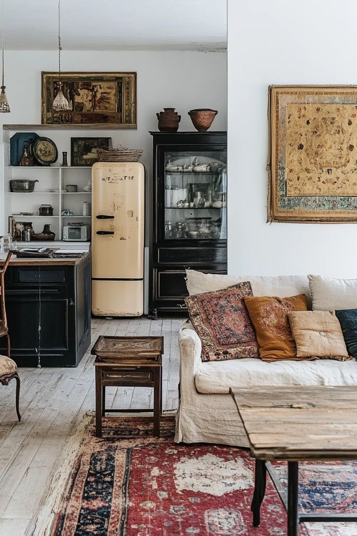 An eclectic living space with a white linen couch, a raw wood coffee table, a patterned rug, and a vintage cream-colored refrigerator.