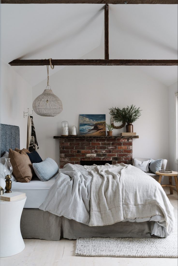 Cozy white bedroom with layered neutral bedding and soft lighting, showing clean white decorating for Fall warmth and simplicity.