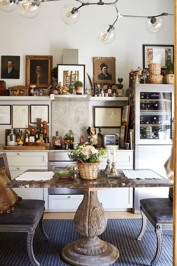 Eclectic fall kitchen with marble dining table, vintage portraits, and natural textures for cozy, dark seasonal decorating.
