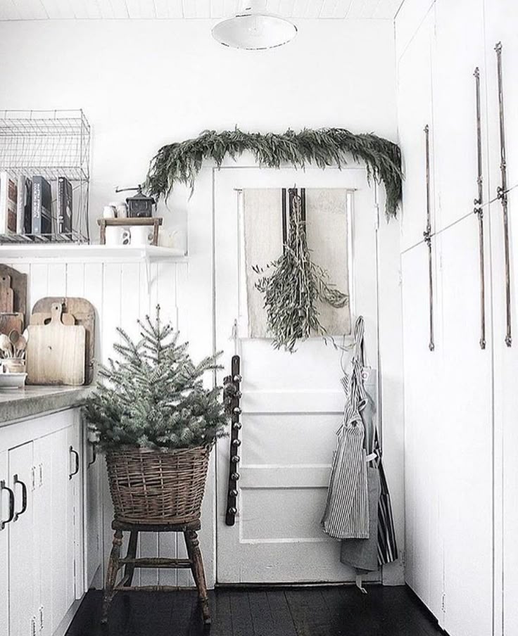 A fireplace mantel decorated with a thick, natural cedar and pine garland, simple candles, and small, unlit paper stars tucked into the branches.