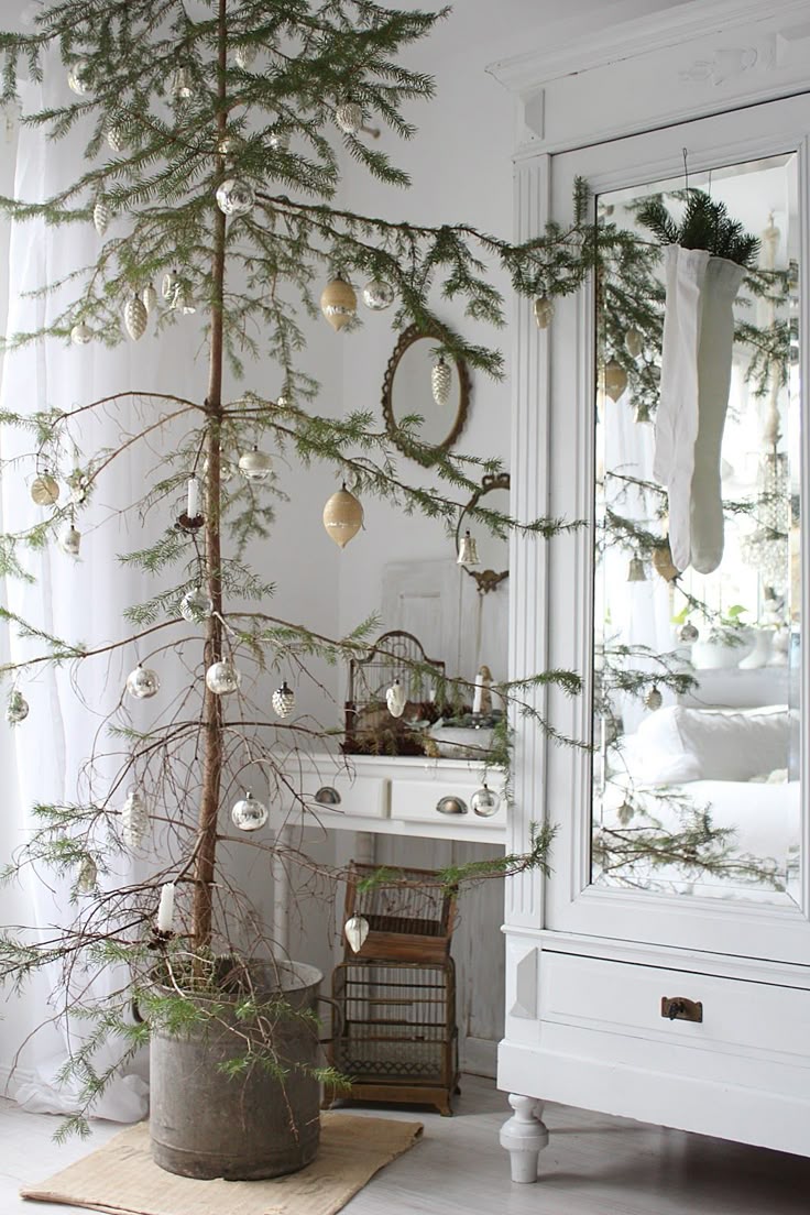 A detailed shot of a sparse evergreen bough decorated with small, handmade wooden ornaments and natural accents like cinnamon sticks and pinecones.
