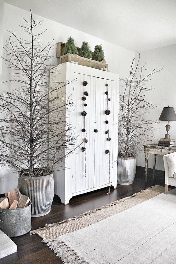 A cozy tabletop vignette featuring a small, folded paper star next to a ceramic vase holding a simple arrangement of fresh eucalyptus and pine branches.