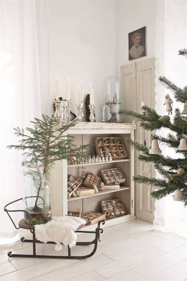 A thick branch trunk secured in a heavy gray concrete pot, covered by a simple, woven cream-colored linen tree skirt.