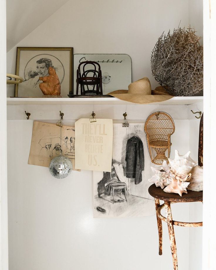 A bathroom interior featuring a light-filled space with a repurposed vintage console vanity, two flanking shaded wall sconces, and a large propped gold mirror.