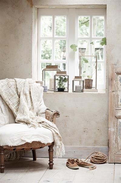 A set of upholstered dining chairs covered in flowing, floor-length white linen slipcovers with a relaxed but elegant drape, paired with a rustic wooden table.