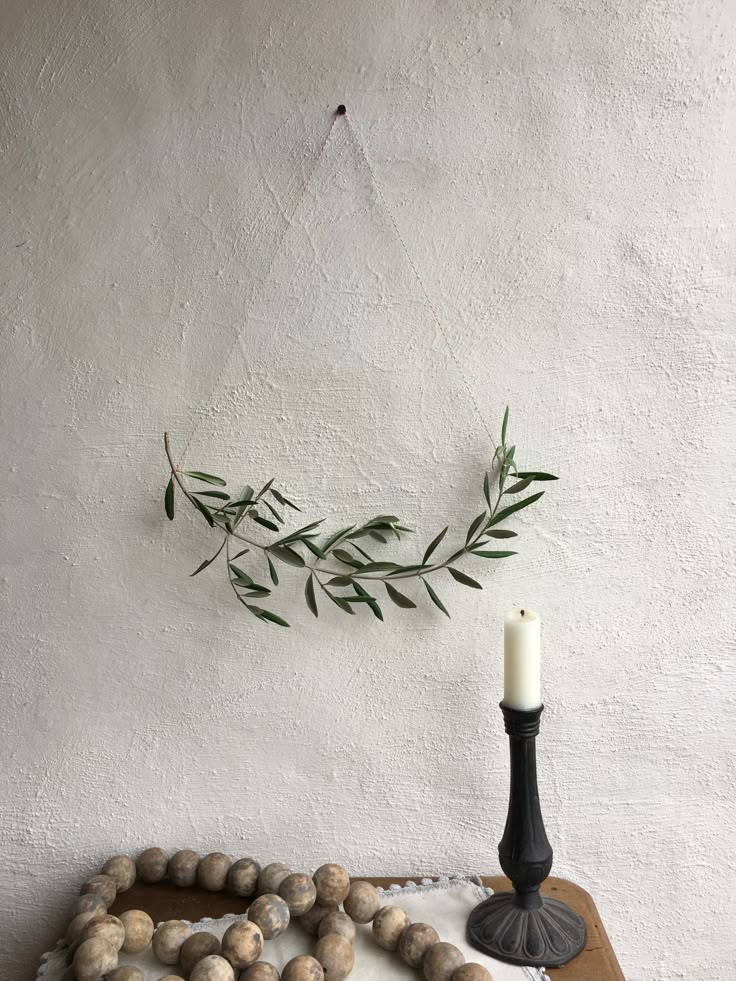 A simple, long olive branch garland with silvery-green leaves laid gracefully across a clean white fireplace mantel, accented by a thin strand of warm LED lights.