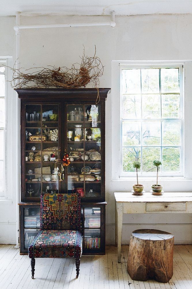 A lush office nook with multiple indoor plants in macramé hangers, a comfortable wicker chair, and a glowing Himalayan salt lamp on a side table.